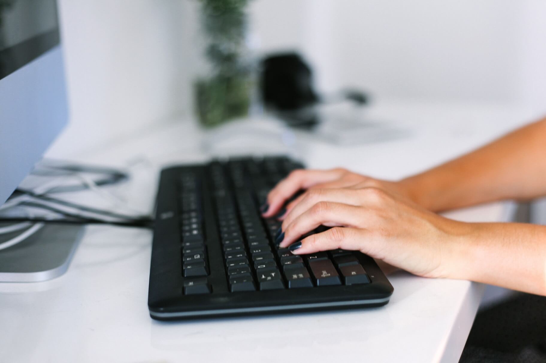 womans hands typing on keyboard at desk working in JDKKPMP